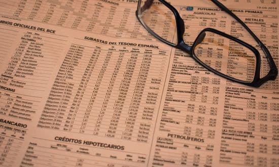 Occhiali su giornale finanziario con tabelle economiche.