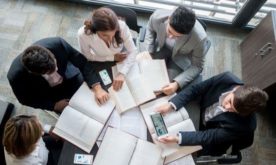 Riunione di lavoro con libri e dispositivi elettronici.