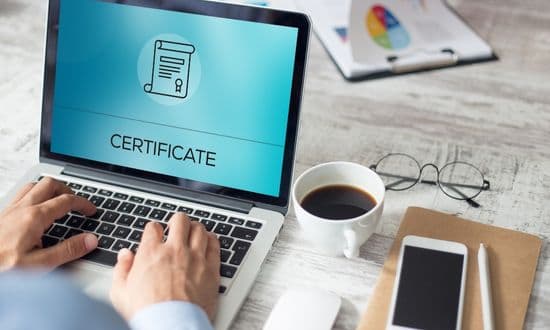 Certificato online su laptop con caffè e smartphone.