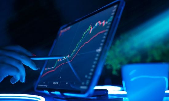 Grafico finanziario su tablet con mano e penna.