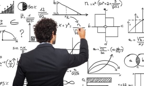 Uomo scrive formule matematiche su lavagna bianca.