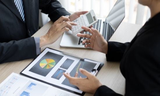 Discussione di analisi finanziaria con grafici e calcolatrice.