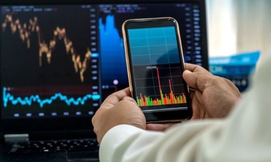 Analisi grafici di borsa su smartphone e computer.