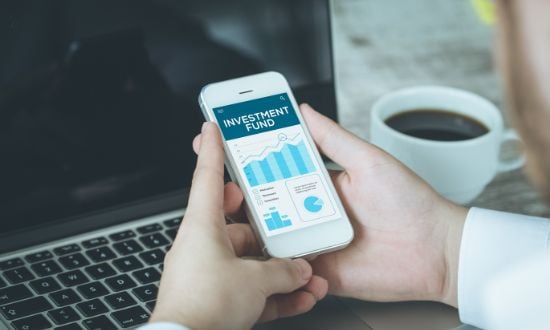 Investimento su smartphone, grafici finanziari, tazza di caffè.