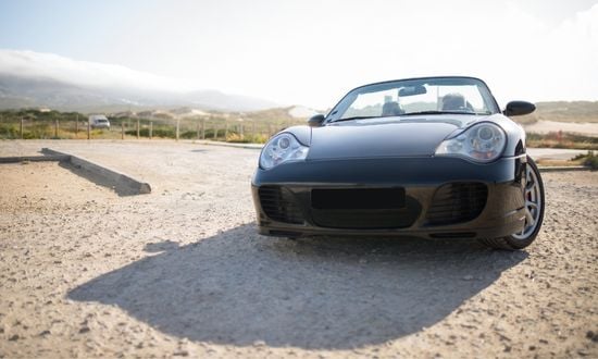 Auto sportiva nera su strada sterrata.