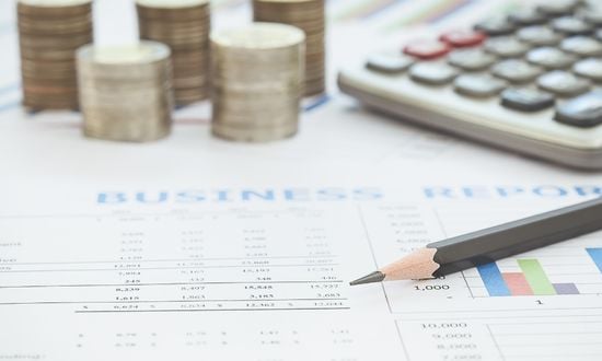 Report aziendale con monete, calcolatrice e matita.