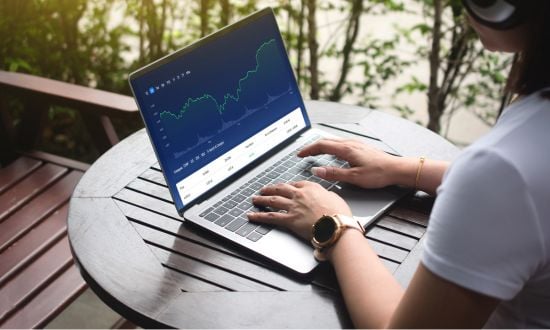 Persona analizza grafici finanziari su laptop all'aperto.