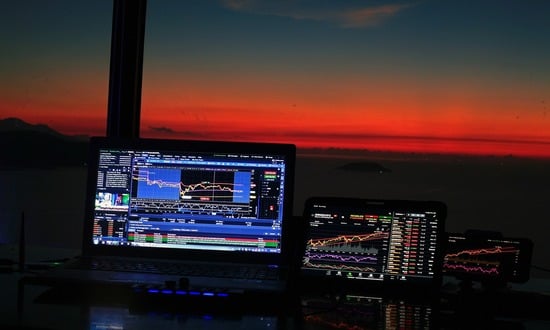 Grafici di trading su laptop e tablet al tramonto.