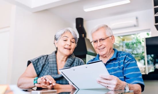 Anziani felici leggono documenti insieme a casa.