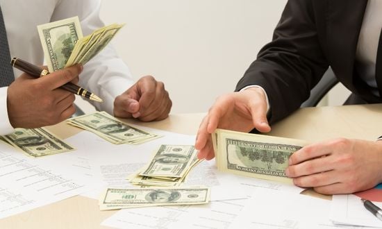 Uomini d'affari contano soldi su un tavolo.