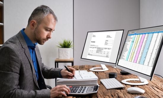 Uomo al lavoro con computer e calcolatrice in ufficio.