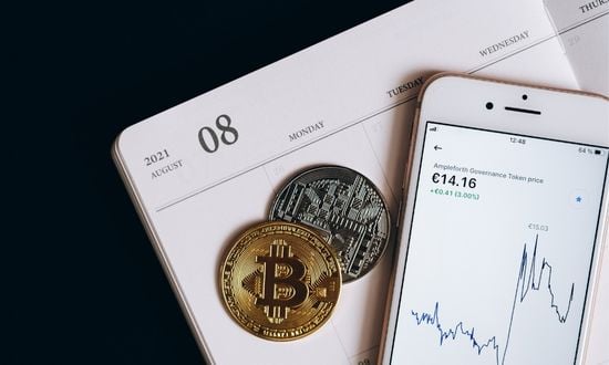 Grafico criptovalute su smartphone con monete Bitcoin.