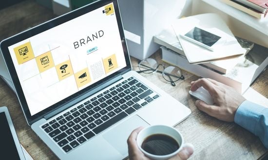 Laptop con grafica di branding e tazza di caffè.