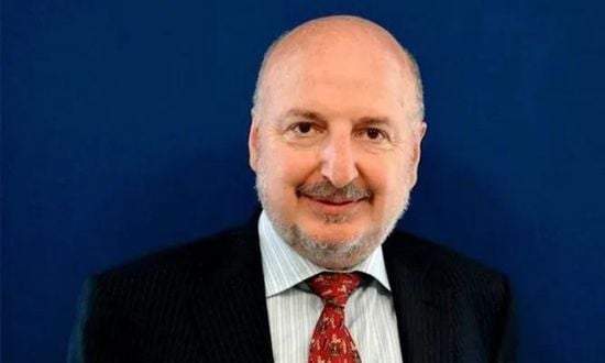 Uomo sorridente in abito formale con cravatta rossa.