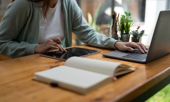 Persona che lavora con laptop e tablet su scrivania.