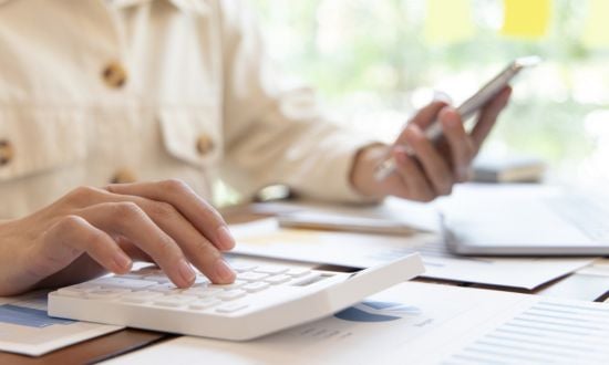 Persona che usa calcolatrice e smartphone per lavoro.