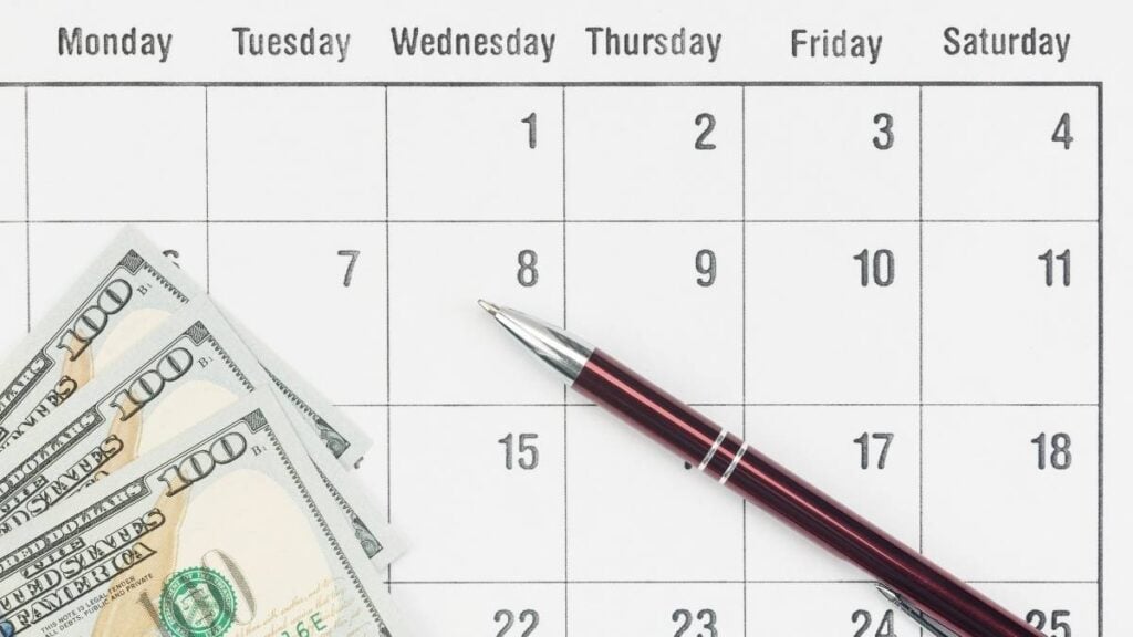 azioni con dividendi mensili - calendario con dollari e una penna